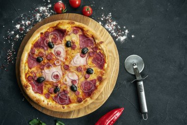 Bol malzemeli pizza: sosis, soğan, mantar, salam, peynir ve dolma biber. Bileşenli pizza siyah arka planda fotokopi alanı ile birlikte.