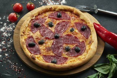 Bol malzemeli pizza: sosis, soğan, mantar, salam, peynir ve dolma biber. Siyah arka planda bileşenleri olan pizza.