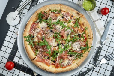 Beyaz arka planda prosciutto di parma, roka ve parmesanlı lezzetli pizza. İtalyan geleneksel mutfağı. Lezzetli yemek düzlüğü. Üst görünüm