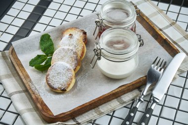 Ev yapımı peynirli kekler ya da reçelli Syrniki, taze meyve ve ekşi krema beyaz arka planda bir el işi kağıdında. Ukrayna mutfağı. Kahvaltı hazır.