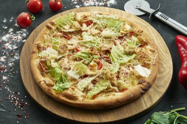 Bol malzemeli pizza: tavuk, marul, kızarmış ekmek, parmesan. Siyah arka planda bileşenleri olan pizza.