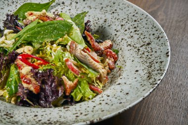 Ispanaklı salata, marul, zeytinyağı, siyah arka planda beyaz seramik tabakta füme yılan balığı. Sağlıklı ve diyet yiyecekler. Deniz ürünleri salatası