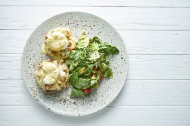 Kremalı sarımsak soslu tost, pastırma ve beyaz ahşap arka planda seramik tabakta marullu haşlanmış yumurta.