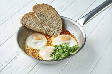 Alışılmadık bir kahvaltı. Tavada ekmek ve domates soslu üç kızarmış yumurta. İsrail Shakuka 'sı. Lezzetli, sağlıklı, diyet yemekleri.