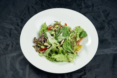 Salatayı ıspanak, mantar, dolma biber, taze fasulye ve bezelye ile siyah arka planda beyaz kasede kapatın. Sağlıklı ve diyet yiyecekler. Vejetaryen