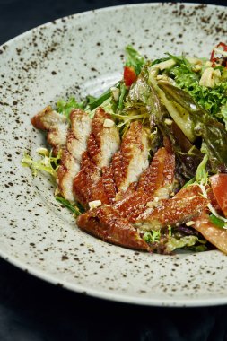 Ispanaklı salata, marul, zeytinyağı, siyah arka planda beyaz seramik tabakta füme yılan balığı. Sağlıklı ve diyet yiyecekler. Deniz ürünleri salatası