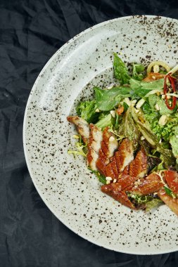 Ispanaklı salata, marul, zeytinyağı, siyah arka planda beyaz seramik tabakta füme yılan balığı. Sağlıklı ve diyet yiyecekler. Deniz ürünleri salatası