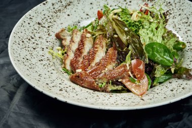 Ispanaklı salata, marul, zeytinyağı, siyah arka planda beyaz seramik tabakta füme yılan balığı. Sağlıklı ve diyet yiyecekler. Deniz ürünleri salatası