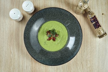 Lezzetli, yeşil avokado kremalı çorba ve ahşap arka planda siyah bir kasede sosis. Diyet ve vejetaryen yemekleri.