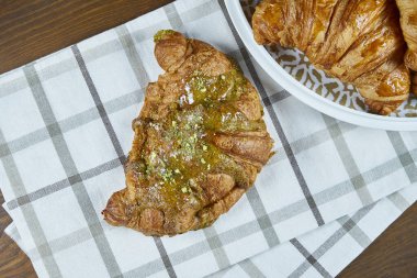 Üst manzara taze pişmiş kruvasan, boğaz ve ahşap arka planda bej kumaşlı şam fıstığı. Fırın kafeleri için yemek fotoğrafçılığı. Görüntüyü kapat.