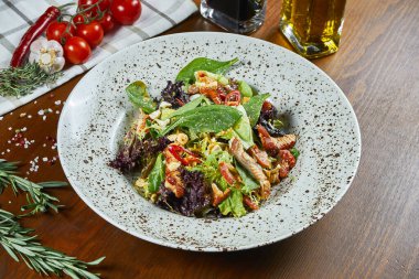 Teriyaki soslu lezzetli yılan balığı salatası ıspanak, kırmızı biber ve ahşap arka planda beyaz bir kasede marul. Deniz ürünleri salatası. Lezzetli ve sağlıklı yiyecekler. Kapat.