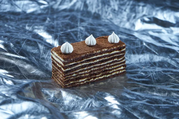 Chocolate cake with layers and pastry cream on Silver background. Slice of delicious. biscuit. Close up. Tasty bakery concept. Selective focus