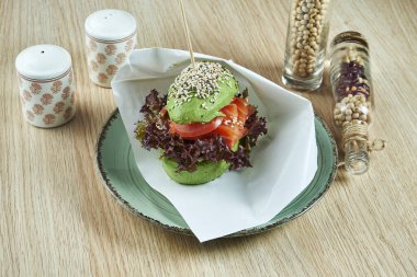 Avokado 'nun yarısından yapılmış olağandışı bir hamburger, somon, domates ve marullu çörekler gibi. Manzarayı kapat. Sağlıklı ve yeşil yiyecek..