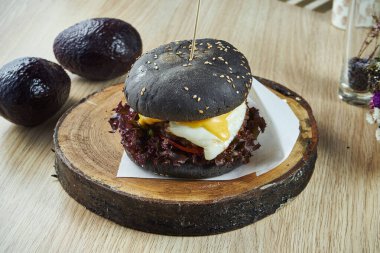 Yumurtalı siyah çörekli hamburger ve ahşap bir tahtanın üzerinde erimiş peynir. Manzarayı kapat. Lezzetli sokak yemekleri
