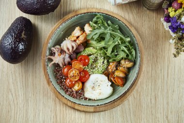 Avokado, kinoa, ahtapot, midye, vişneli domates ve haşlanmış yumurta ile deniz ürünleri kasesi. Sağlıklı ve dengeli yiyeceklerle dolu Buda kasesi. Üst manzara, düz uzanma