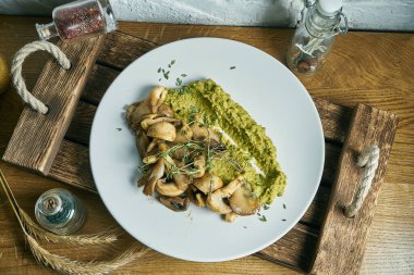 Brokoli püresi, ahşap bir tabakta kızartılmış mantarla birlikte. Vejetaryen yemeği. Üst manzara, düz uzanma