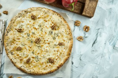 Hafif arka planda cevizli dört peynirli İtalyan pizzası. Pizza, sos ve domatesli kompozisyon. Kopyalama alanı olan üst görünüm. Düz yatıyordu. Quattro Fromaggi