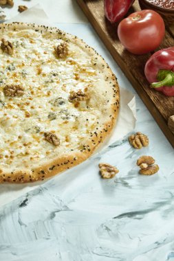 Hafif arka planda cevizli dört peynirli İtalyan pizzası. Pizza, sos ve domatesli kompozisyon. Kopyalama alanı olan üst görünüm. Düz yatıyordu. Quattro Fromaggi