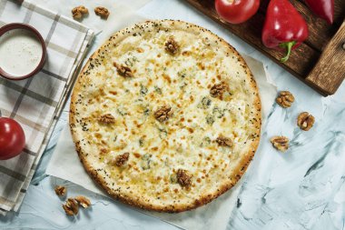 Hafif arka planda cevizli dört peynirli İtalyan pizzası. Pizza, sos ve domatesli kompozisyon. Kopyalama alanı olan üst görünüm. Düz yatıyordu. Quattro Fromaggi