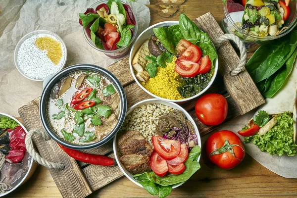 Composition with a dinner table with vegetarian dishes: bowl, dessert and miso soup on a gray cloth. Healthy and balanced food. Menu photo, top view