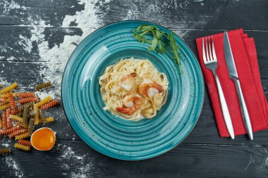 Mavi tabakta karides ve krema soslu ev yapımı iştah açıcı makarna. Yaklaş, üstten bak. İtalyan spagettisi, tarif için fotoğraf.