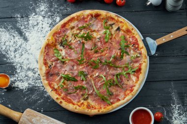 Kırmızı soslu fırında pizza ve siyah ahşap arka planda eritilmiş peynir içerikli kompozisyon. Üst görünüm