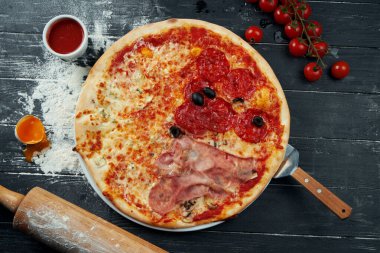 Salamlı fırınlanmış pizza, prosciutto ve kırmızı soslu tavuk ve siyah ahşap bir arka planda eritilmiş peynir içerikli kompozisyon. Üst görünüm