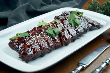 Ahşap arka planda beyaz tabakta barbekü soslu leziz bbq pişmiş pirzolalara yakından bakın. Klasik Amerikan Barbekü Domuz eti ve sindirim maddeleri.