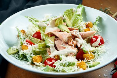 Servis edilen Sezar salatasına yakından bakın. Ahşap arka planda tütsülenmiş somon balığı. Lezzetli deniz ürünleri salatası.