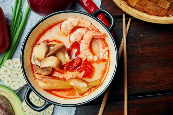 Top view tom yam with shrimp, seafood, coconut milk and chili pepper in composition with ingridients. Popular hot and sour Thai soup. Copy space. Tom yum