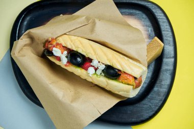 Karamelli soğanlı klasik Amerikan sosislisi, çedar peyniri, hardal ve yanında renkli arkaplanda patates olan ketçap. Fast food