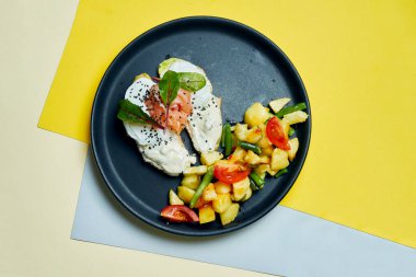 Klasik Avrupai kahvaltı. Krem peynirli tost, somon balığı ve haşlanmış yumurta ve siyah bir tabakta domatesli fırında patates.