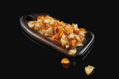 Tahta tepside iştah açıcı sebze cipsleri. Siyah arka planda patates, mantar ve havuç cipsi. Bira çerezi. Menü için fotoğraf