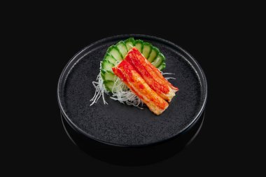 Klasik çiğ yengeç sashimi, siyah arka planda siyah seramik tabakta salatalık ve daikon turpu. Geleneksel Japon yemekleri. Menü için fotoğraf