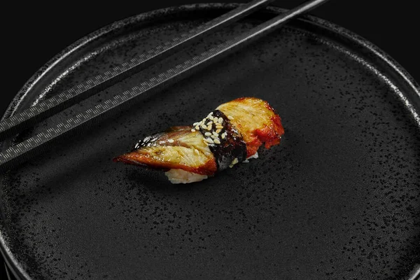 黒のおしゃれな箸で黒のセラミックプレートに鰻とご飯がのった定番の寿司 伝統的な和食 メニューの写真 — ストック写真