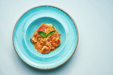 Domatesli ve karidesli iştah açıcı makarna, gri arka planda mavi kasede parmesan peyniri. İtalyan mutfağı