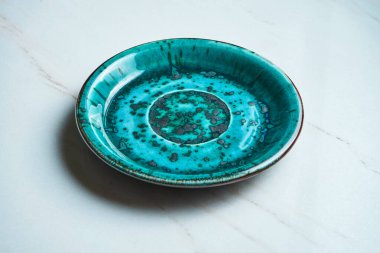 Gri mermer arka planda el yapımı boş mavi seramik plakayı kapat. Uzayı metin için kopyala. Şık mutfak aletleri