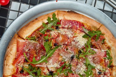 Beyaz arka planda prosciutto di parma, roka ve parmesanlı lezzetli pizza. İtalyan geleneksel mutfağı. Lezzetli yemek düzlüğü. Üst görünüm