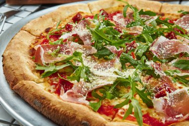 Beyaz arka planda prosciutto di parma, roka ve parmesanlı lezzetli pizza. İtalyan geleneksel mutfağı. Lezzetli yemek düzlüğü. Üst görünüm