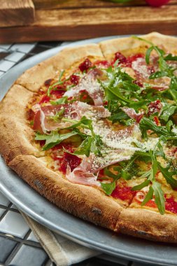 Beyaz arka planda prosciutto di parma, roka ve parmesanlı lezzetli pizza. İtalyan geleneksel mutfağı. Lezzetli yemek düzlüğü. Üst görünüm