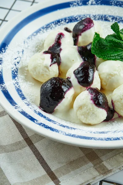 Traditional Ukrainian lazy dumplings. Dumplings with cottage cheese in a white plate on a white wooden background with berry jam. Tasty and sweet breakfast. Vareniki