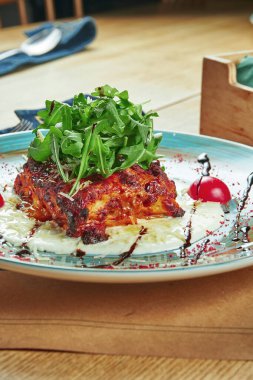 Ev yapımı iştah açıcı bir porsiyon, sadece et ve peynirli fırında lazanya, krem sos ve ahşap zemin üzerinde seramik bir tabakta roka. Restoran masası ayarı