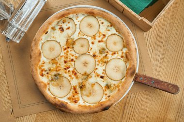 Beyaz soslu iştah açıcı pizza, armut ve ahşap zemin üzerinde çıtır çıtır Gorgonzola peyniri. Restoran masası. Üst görünüm
