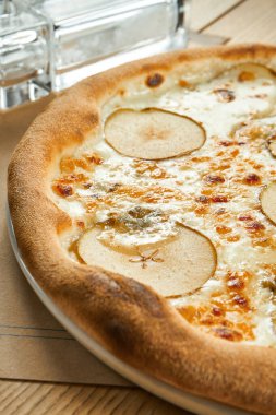 Beyaz soslu iştah açıcı pizza, armut ve ahşap zemin üzerinde çıtır çıtır Gorgonzola peyniri. Restoran masası. Yaklaş, seçici odaklanma