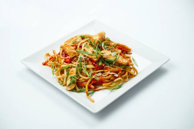 Tatlı ve ekşi soslu lezzetli udon eriştesi sebzeli ve gri arka planda tavuk beyazı tabağı. Kopyalama alanı olan üst görünüm