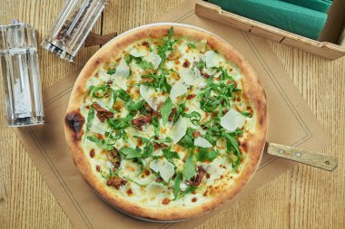Yabani mantarlı fırında pizza, parmesan peyniri ve ahşap zemin üzerinde çıtır çıtır roka. Restoran masası. Üst görünüm