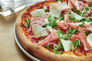 Prosciutto di parma, parmesan peyniri ve ahşap zemin üzerinde çıtır çıtır roka ile aperatif pizza. Restoran masası. Yaklaş, seçici odaklanma