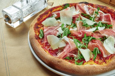 Prosciutto di parma, parmesan peyniri ve ahşap zemin üzerinde çıtır çıtır roka ile aperatif pizza. Restoran masası. Yaklaş, seçici odaklanma
