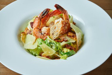 Sezar 'ı karides, pastırma, marul, parmesan ve kızarmış ekmekle iştah açıcı. Deniz ürünleri salatası. Görüntüyü kapat