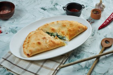 Gri arka planda beyaz tabakta çıtır çıtır pişmiş calzone pizza. Restoran servisi..
